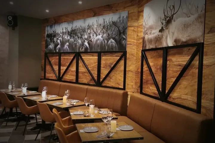 Crosta Restaurant Alta: lyse skinnbenker og trebord under veggbilder av reinsdyr