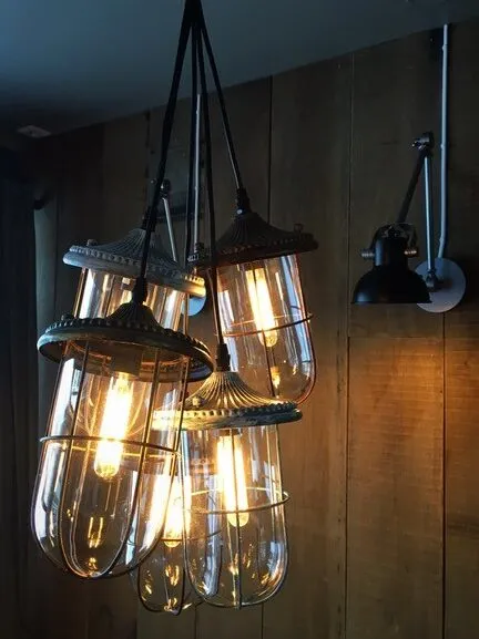 Tavernan Alta: hengende glasslamper med synlige glødetråder foran en trevegg