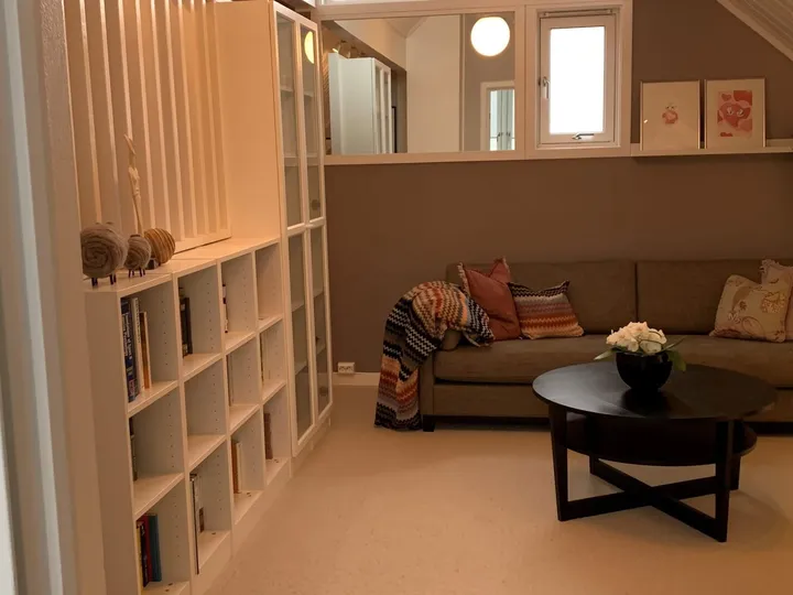 Loftstue: loftsstue med brun sofa, rundt svart salongbord og bokhylle