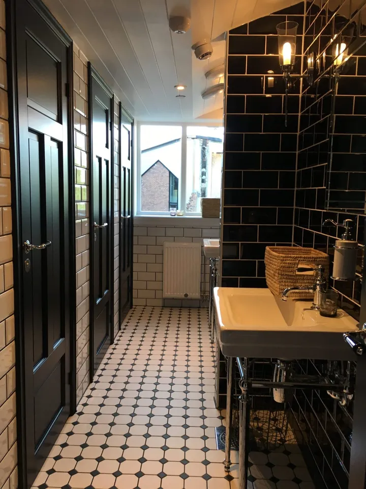 Vintage Kitchen: baderom med mørke fliser, hvit servant, svart dør og svart-hvitt gulv