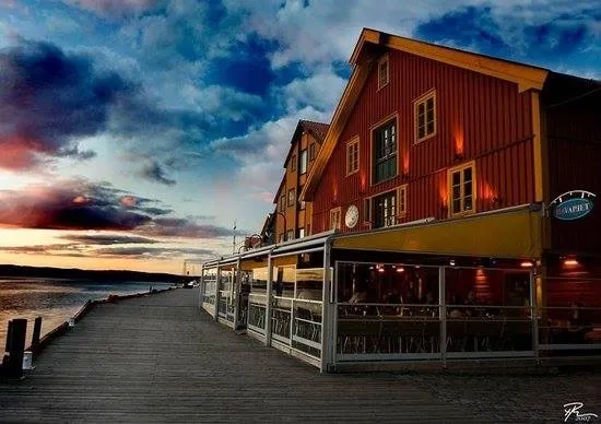 Havariet: rød trebygning ved en brygge i solnedgang, med uteservering