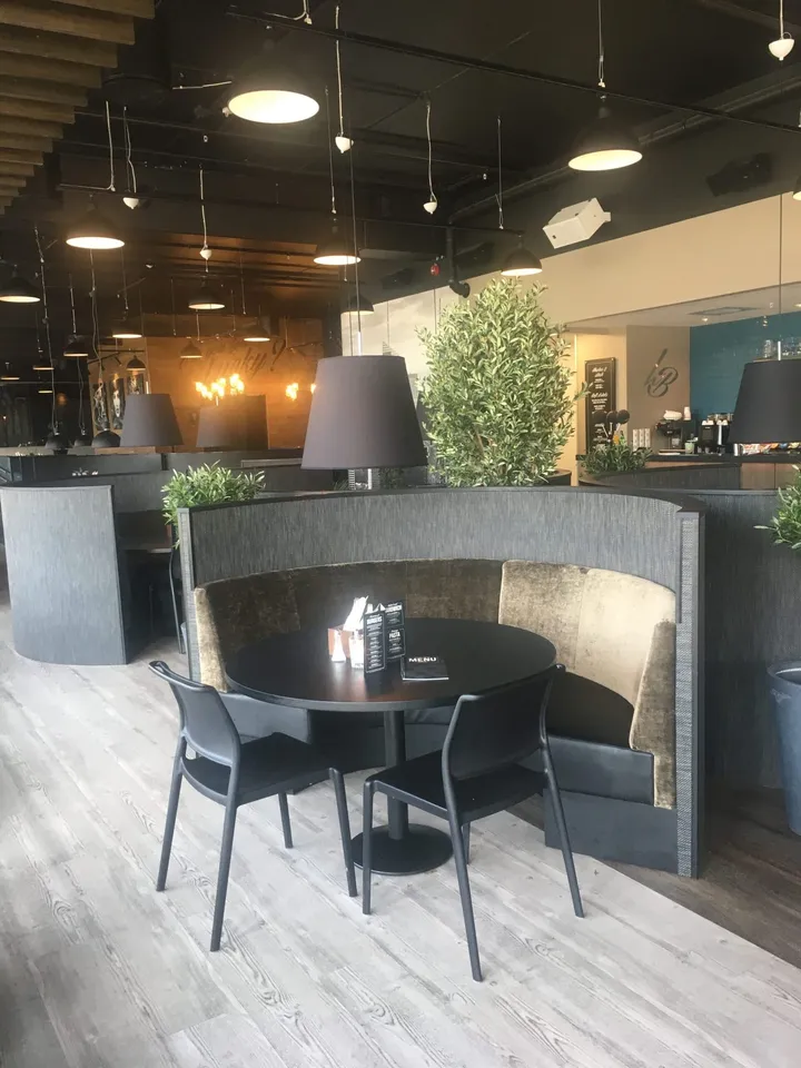 Lucky Bowl: rund polstret sittenisje med rundt bord, sorte stoler og store lamper