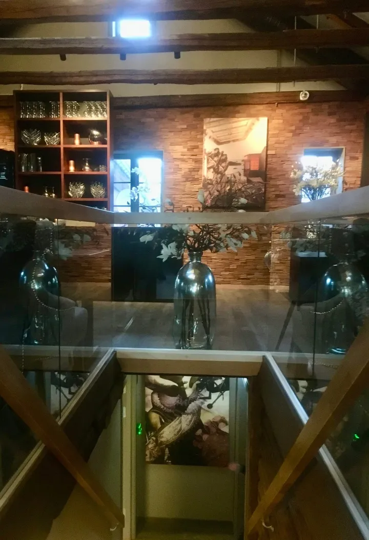Havariet: glassrekkverk med store glassvaser foran en murvegg med innrammede bilder