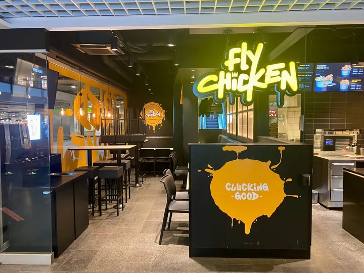 Fly Chicken: restaurant med neonskiltet «Fly Chicken» og en gul disk med teksten «Clucking good»