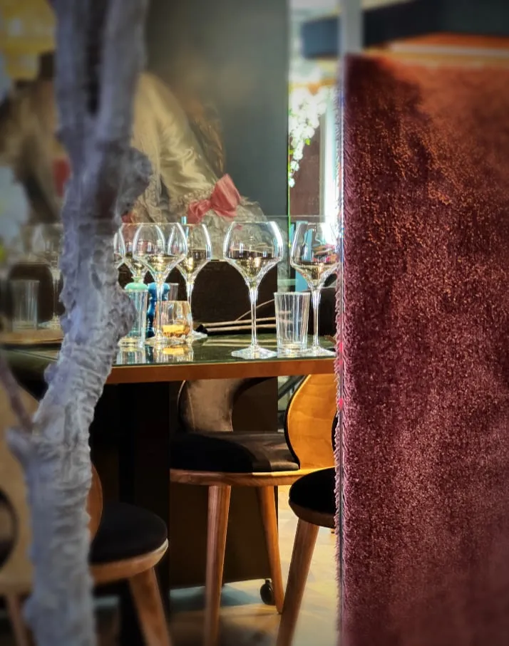 Alma restaurant: dekket bord med vinglass og skinnstoler, med rødt tekstil til høyre