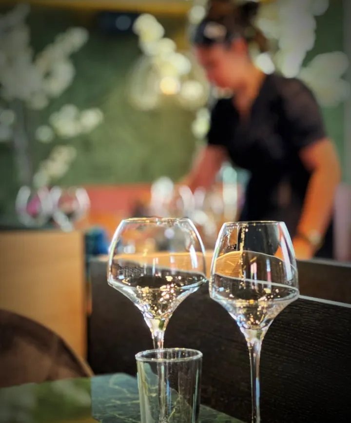 Alma restaurant: to vinglass på en disk, med en uskarp person i bakgrunnen