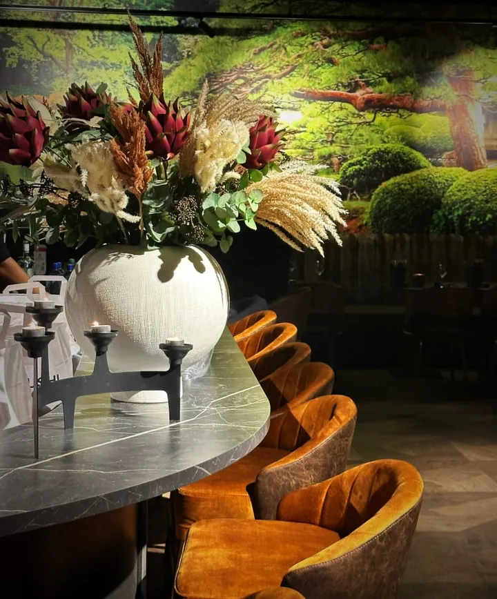 Japo Sushi: vase med tørkede blomster på et bord, med oransje fløyelsstoler bak