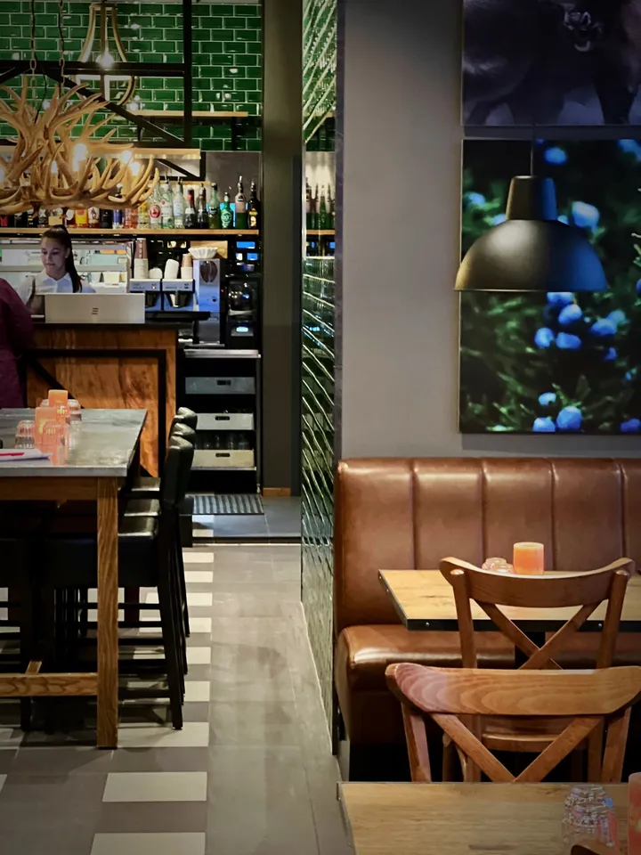 Crosta Restaurant Alta: restaurant med grønne fliser, brun skinnbenk, trestoler og et stort bilde av blåbær på veggen